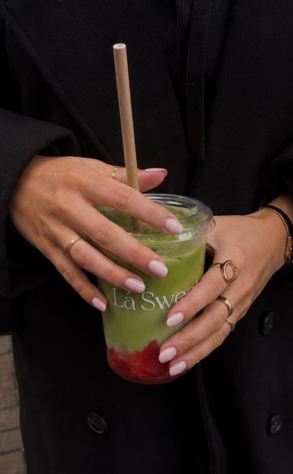Iced strawberry matcha van Lá Sweet, vastgehouden in twee handen